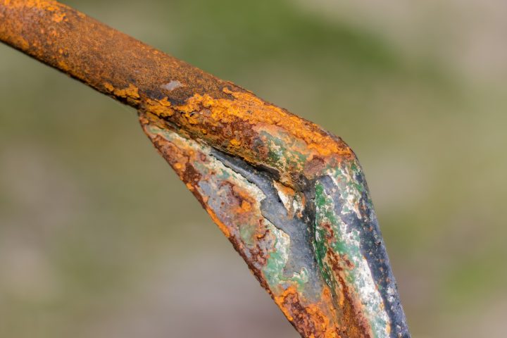 a metal rode has green and orange oxidation against a blurry background