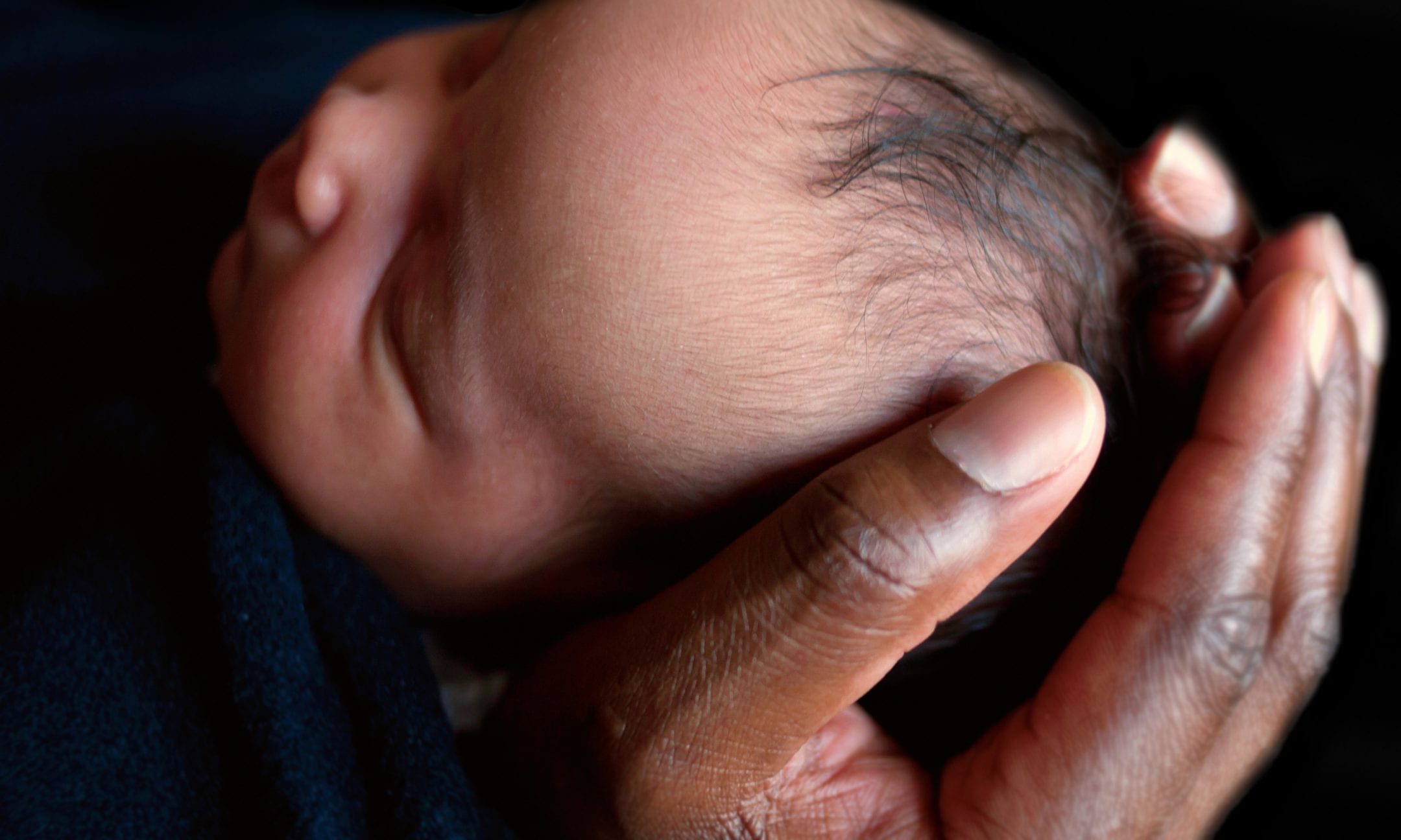 Newborn baby cradled in man's hands